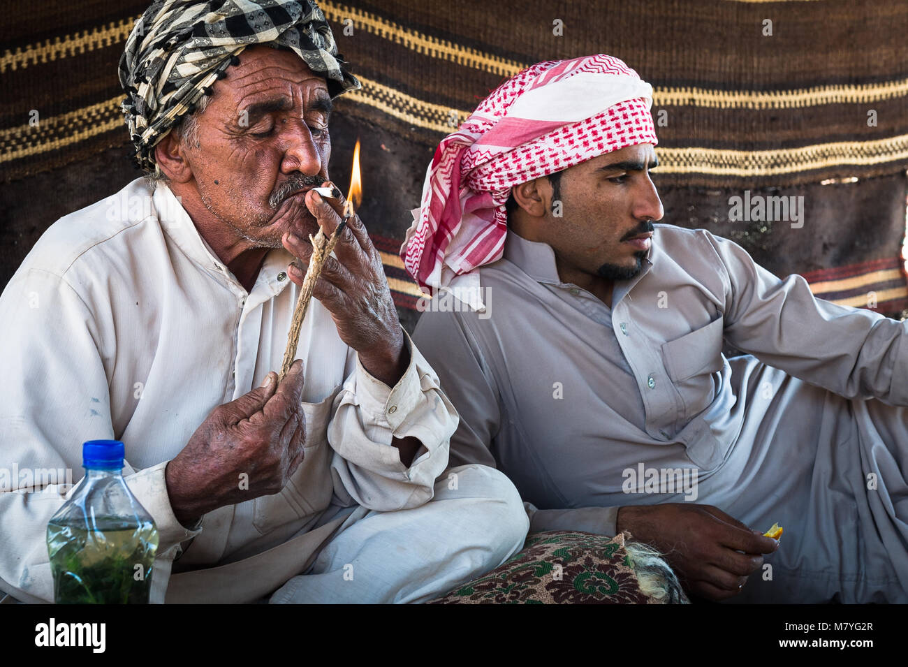 Deux man smoking a sigaret et relaxant dans leur tente bédouine dans le Wadi Rum en Jordanie. Banque D'Images