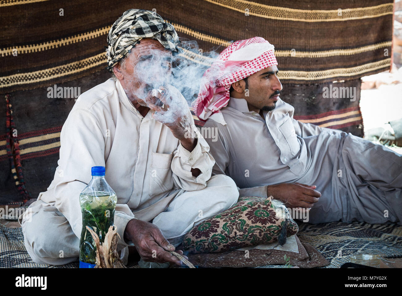 Deux man smoking a sigaret et relaxant dans leur tente bédouine dans le Wadi Rum en Jordanie. Banque D'Images