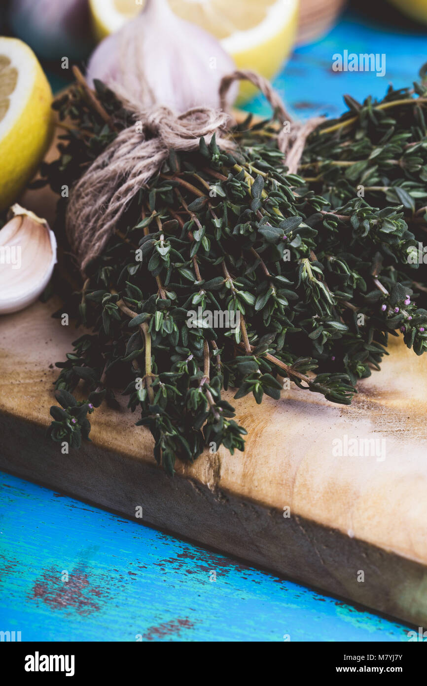 Bouquet de thym, de citrons frais et l'ail sur planche à découper en bois. Les ingrédients d'une cuisine méditerranéenne traditionnelle Banque D'Images