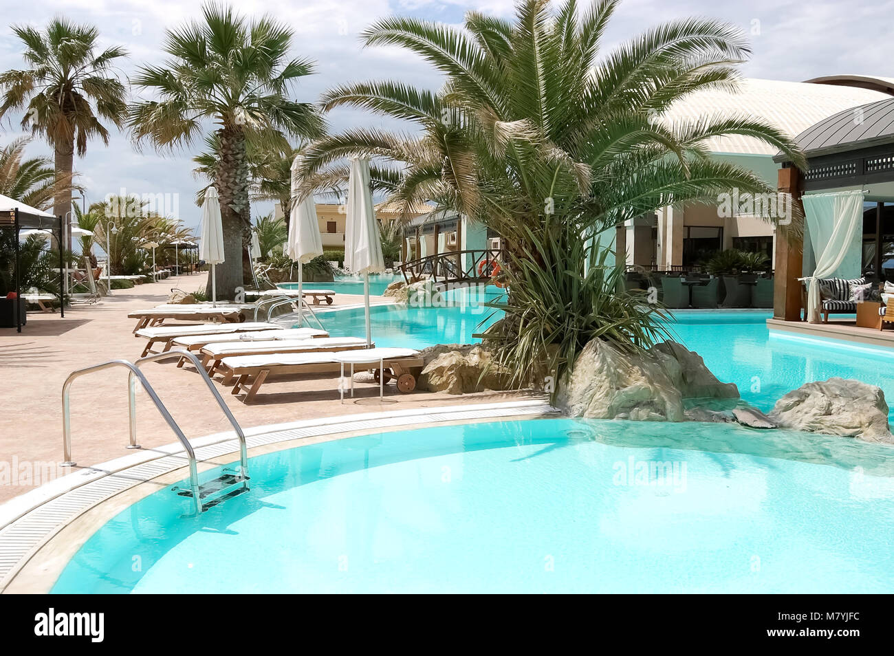 Palmiers, un pont et des piscines aux eaux turquoises dans un hôtel moderne grecque. Banque D'Images