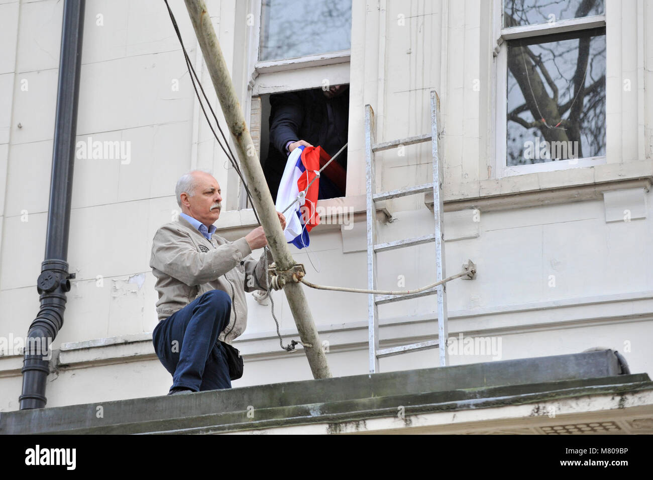 Londres, Royaume-Uni. 14 mars 2018. Un ouvrier remplace un drapeau endommagé à l'extérieur de l'affiche Ambassade de Russie dans Kensington. La Grande-Bretagne a donné 23 diplomates russes une semaine pour quitter le pays après l'attaque de Sergueï Skripal ex-espion et sa fille Julia avec le gaz neurotoxique à Salisbury. Crédit : Stephen Chung / Alamy Live News Banque D'Images