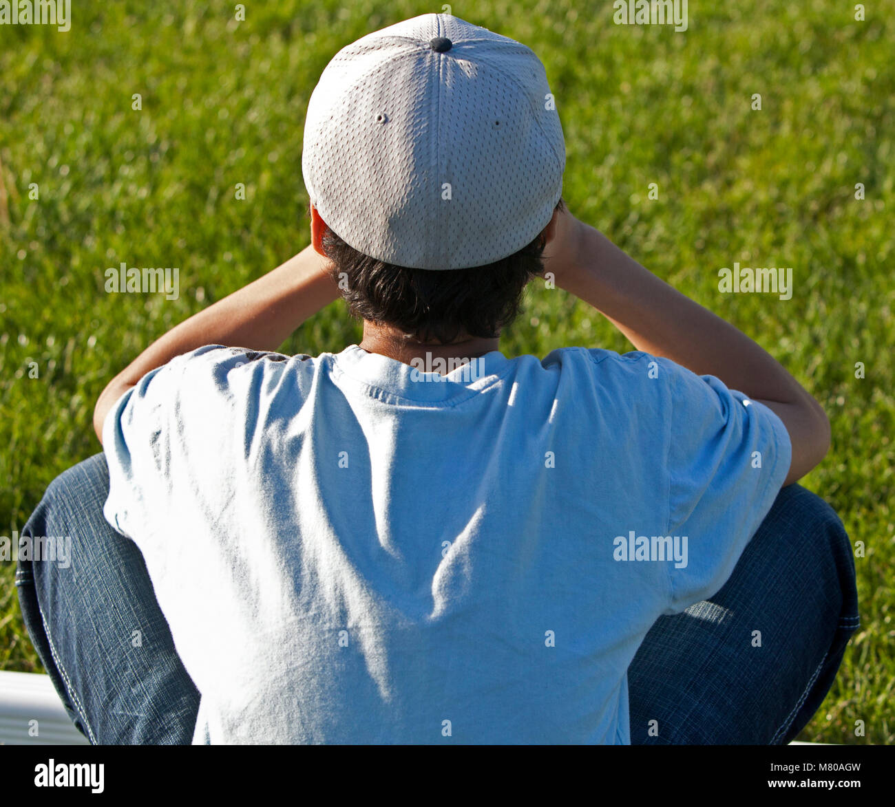 Garçon assis seul dans l'herbe en colère et triste Banque D'Images