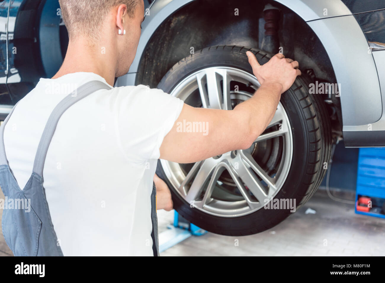 Faible angle de vue de la part d'un mécanicien automobile qualifié détenant un pneu Banque D'Images