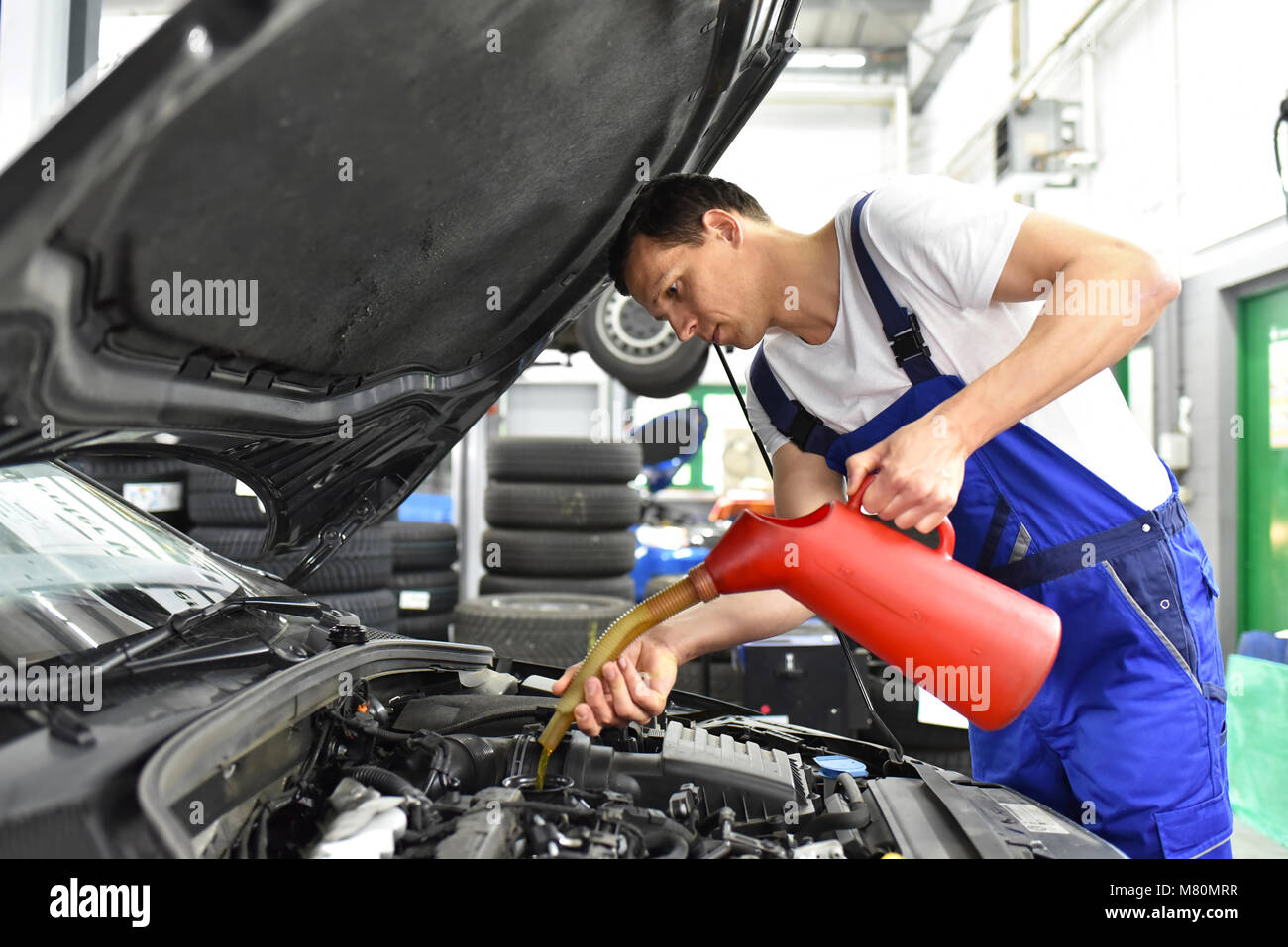 Le changement d'huile du moteur d'une voiture à un atelier par un mécanicien professionnel - le service après-vente Banque D'Images