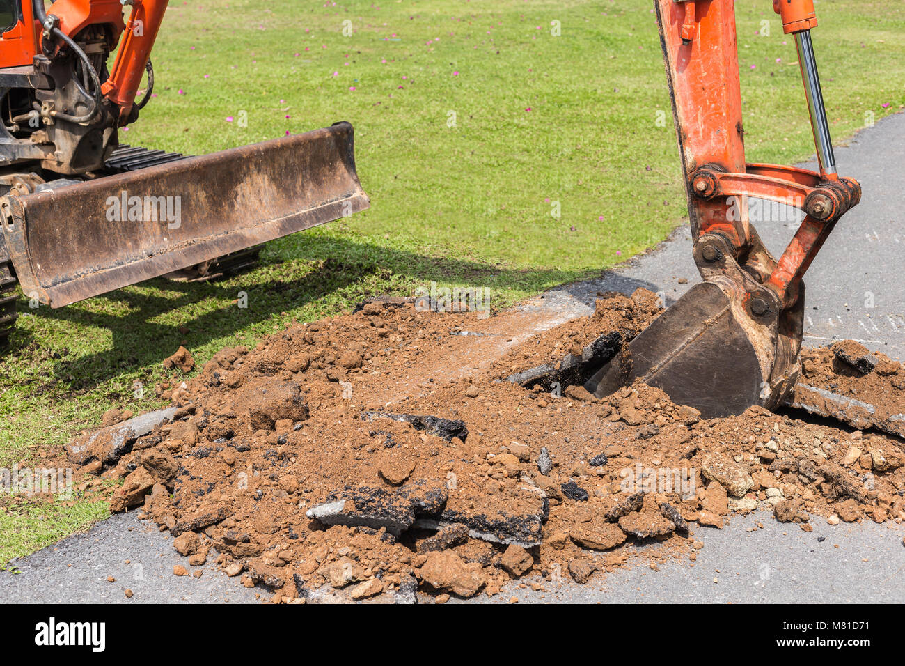 La machine fonctionne de la pelle pour creuser le sol et réparer la route dans le parc public Banque D'Images