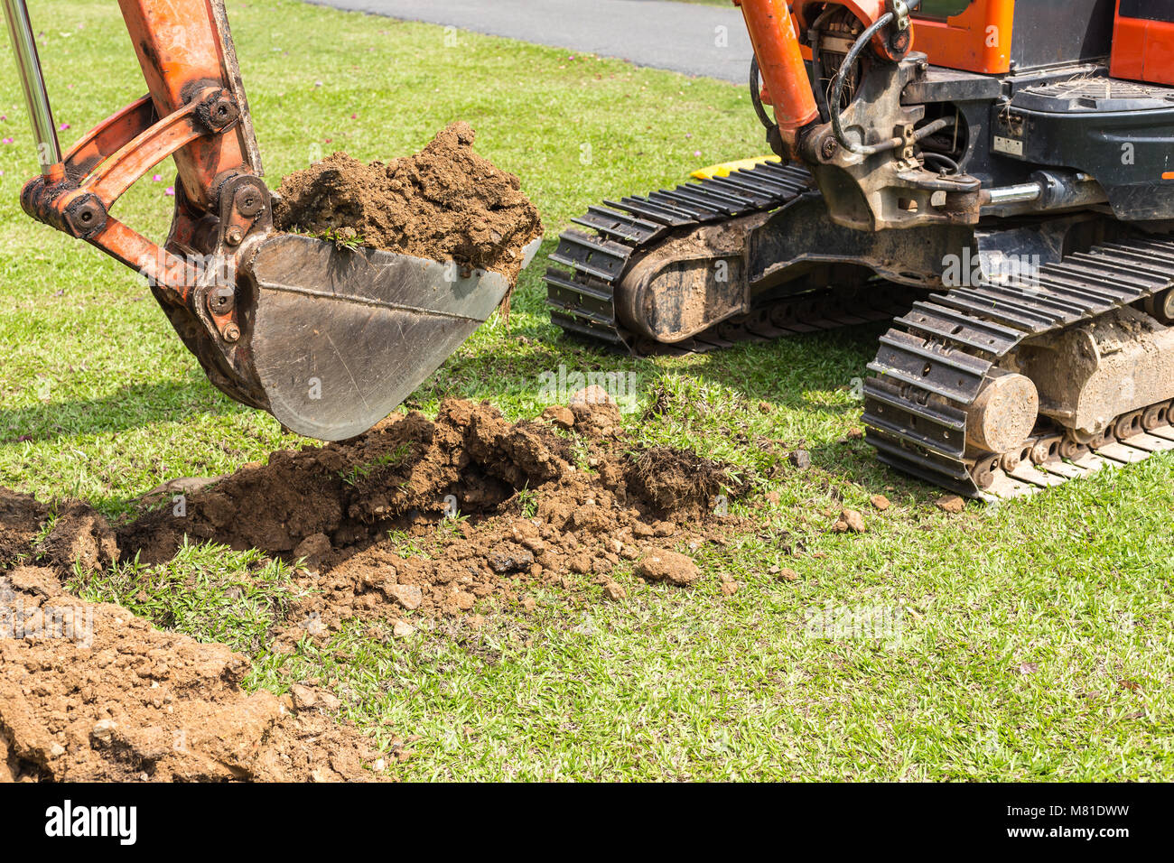 La machine fonctionne de la pelle pour creuser le sol et réparer la route dans le parc public Banque D'Images