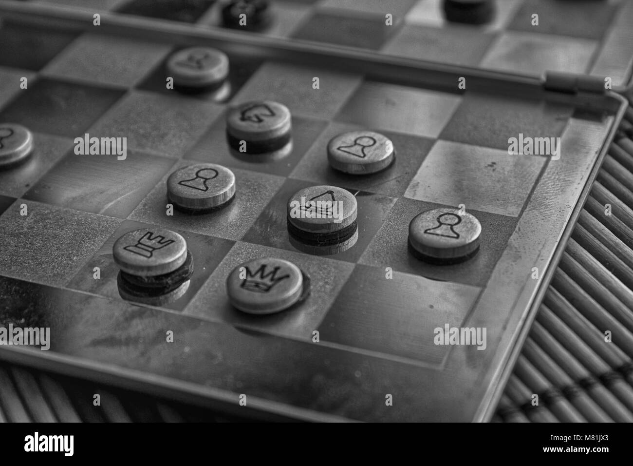 Photo monochrome avec une photo d'un conseil d'acier d'échecs et des pièces de métal, pièces d'échecs sur un échiquier avec réflexion. Banque D'Images
