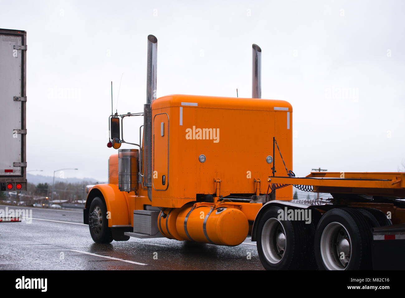 Orange Comfort bonnet américain professionnel gros camion semi ancien style  classique avec conduite de camion semi-remorque à plateau sur autoroute en  temps de pluie pour loa Photo Stock - Alamy