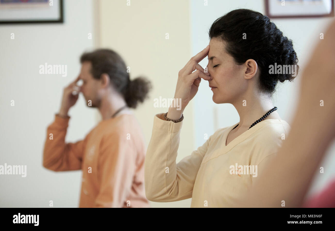 Un profil plus près, deux jeunes gens pratiquant la respiration yogique technique appelée Pranayama, assis avec les jambes croisées, dos droit, les yeux fermés Banque D'Images