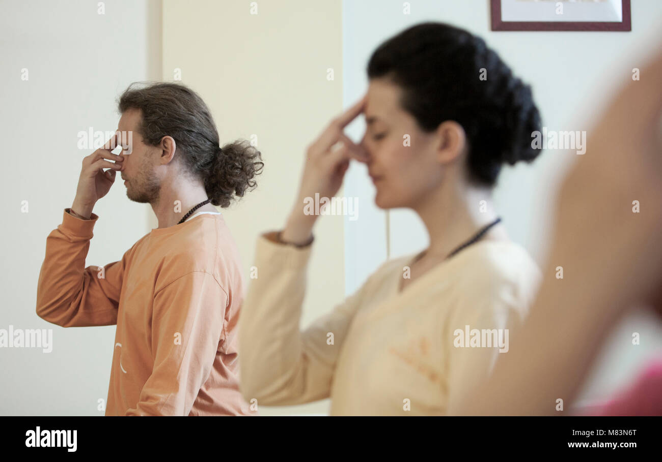 Un profil plus près, deux jeunes gens pratiquant la respiration yogique technique appelée Pranayama, assis avec les jambes croisées, dos droit, les yeux fermés Banque D'Images