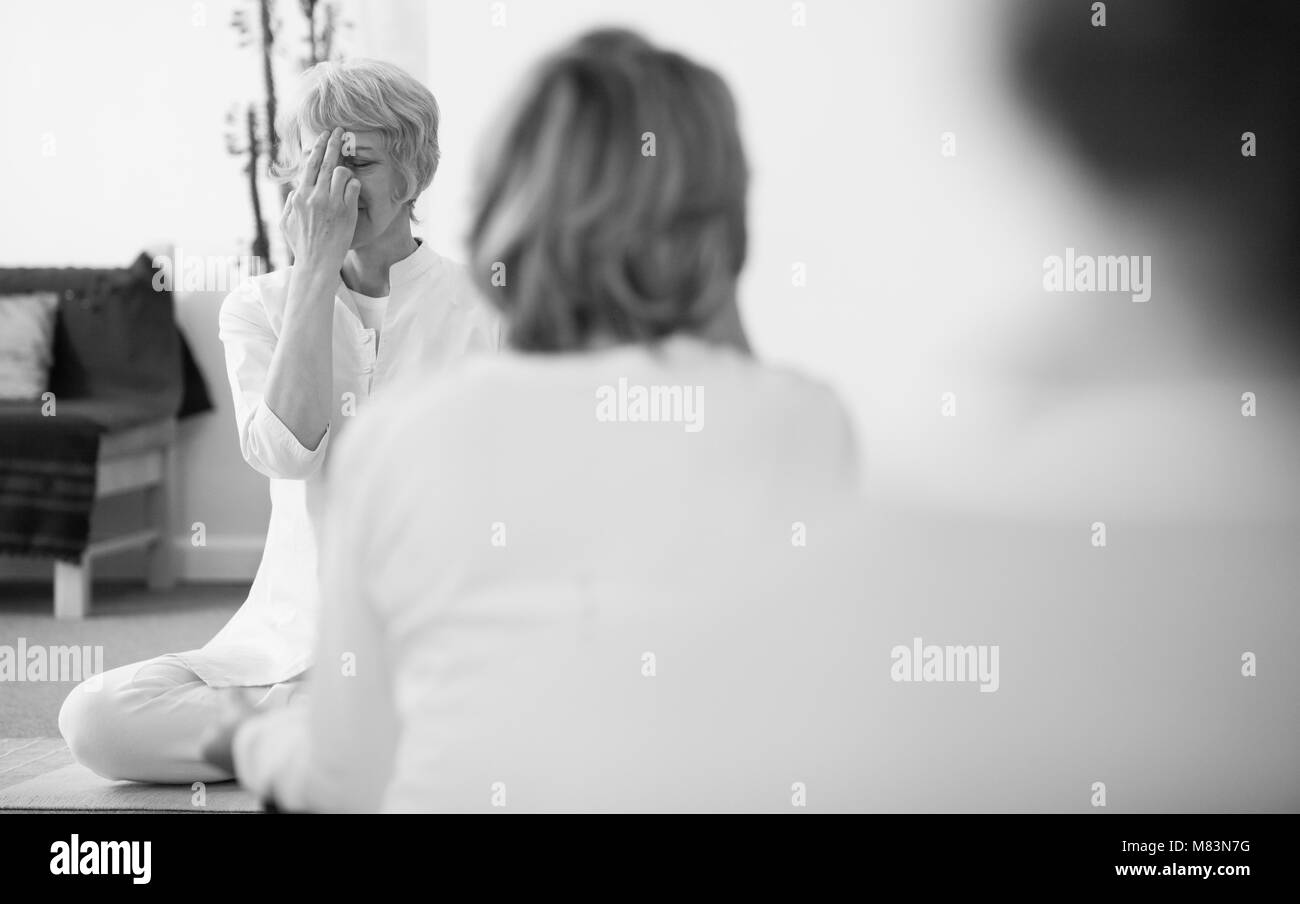Image en noir et blanc d'un groupe de personnes pratiquant la respiration yogique technique appelée Pranayama, assis avec les jambes croisées, dos droit, les yeux fermés Banque D'Images