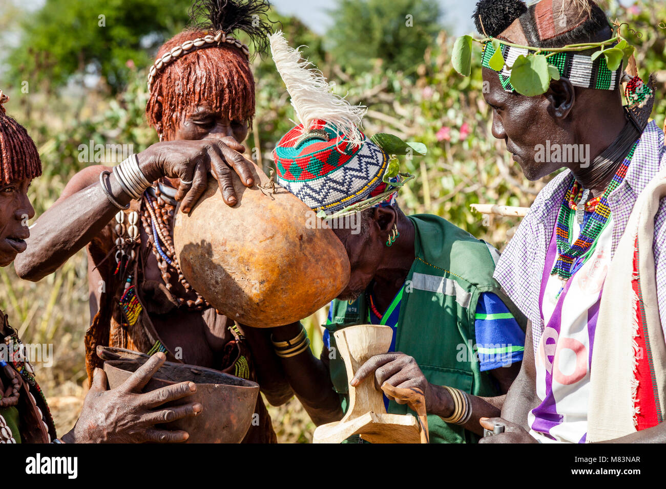 Des invités d'honneur lors d'une cérémonie de saut Bull sont offert une bière locale à boire, Dimeka, vallée de l'Omo, Ethiopie Banque D'Images