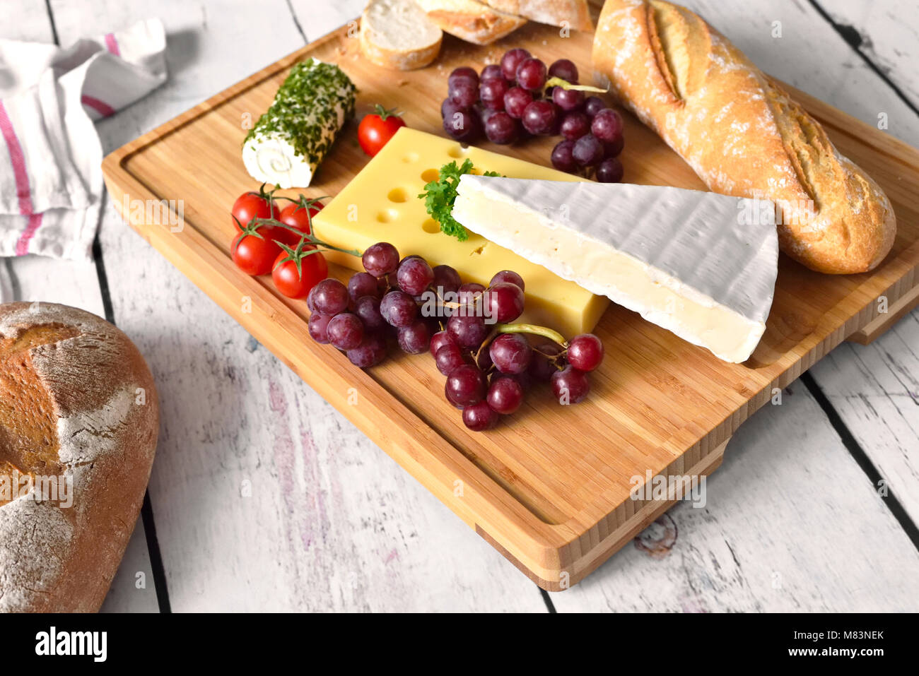 Assiette de fromages, variation de fromage frais, Camembert, fromage à la crème et fromage Leerdamer sur une planche à découper en bois. Baguette, pain frais ou le dîner. Banque D'Images