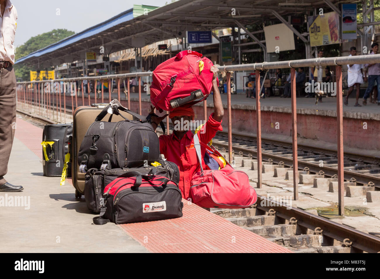 Porter, au chemin de fer la gare de Kerala debout sur la ligne de chemin de fer après avoir mené un ses bagages à travers elle. Banque D'Images
