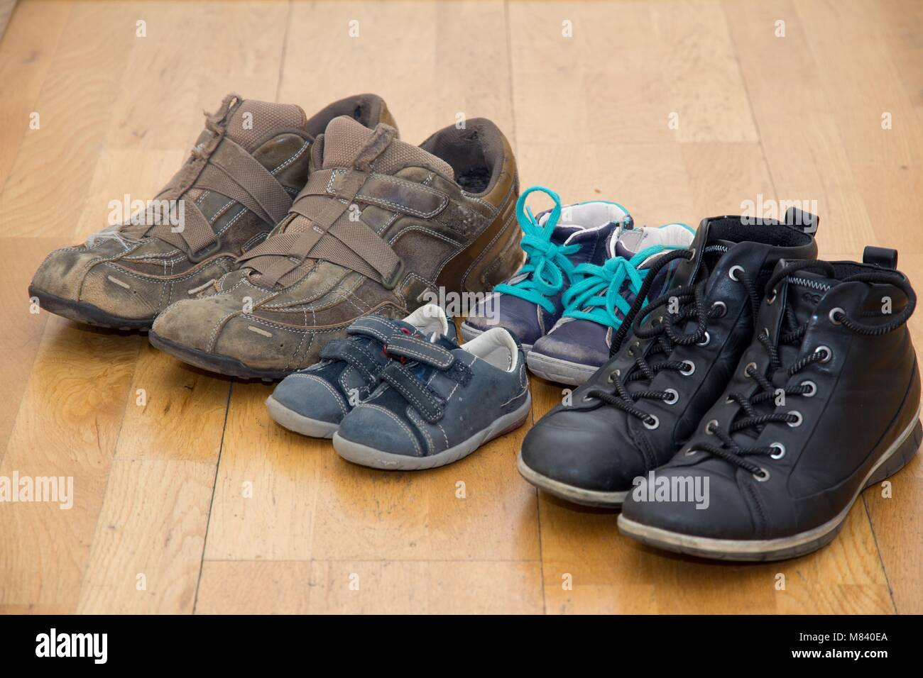 Une variété d'employés occasionnels chaussures pour toute la famille, composée de papa, maman,et deux petits souliers, disposés en une rangée sur du parquet à la maison Banque D'Images