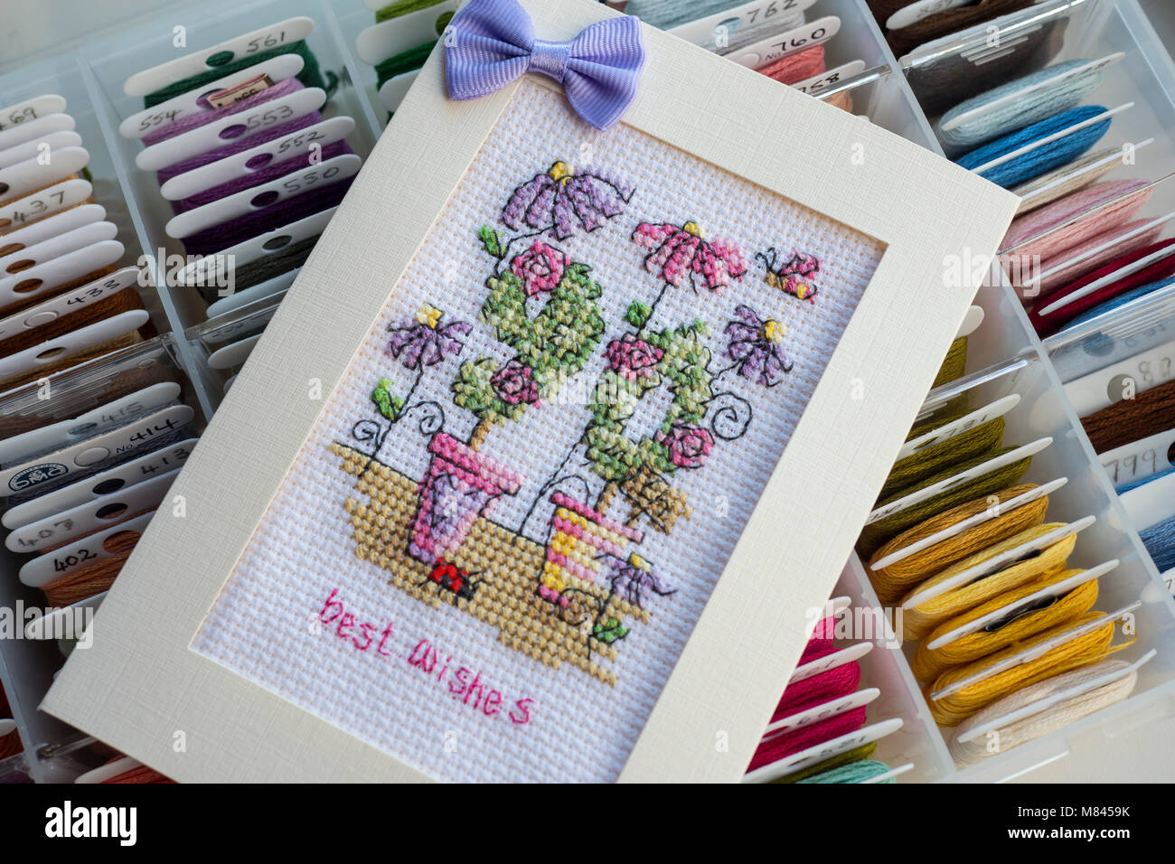 Fils à broder pour cross stitch dans une boîte de rangement avec rempli de croix faite dans une carte Banque D'Images