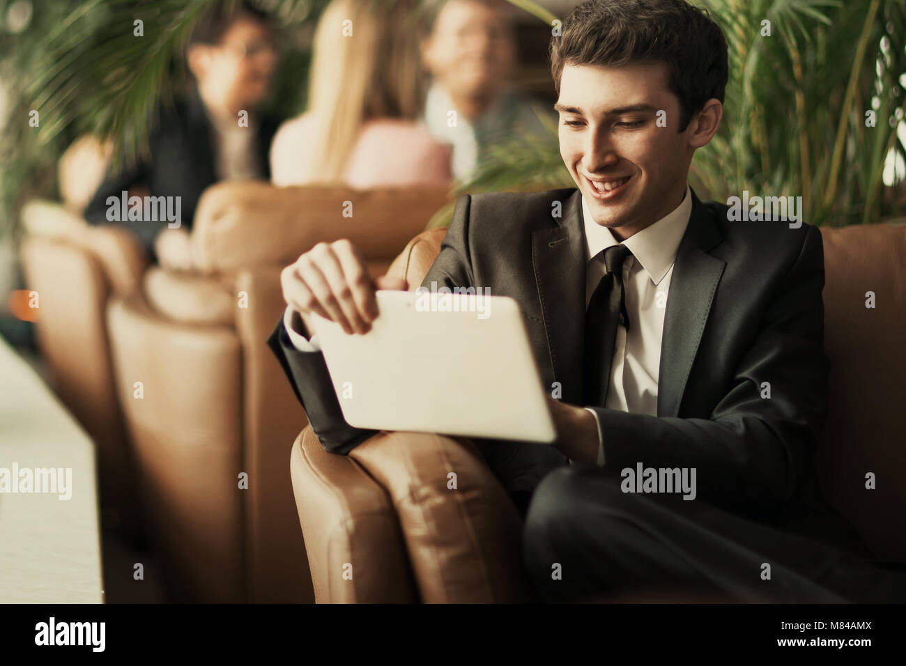 Entrepreneur-novice avec une tablette numérique assis sur le canapé dans le hall d'un bureau moderne Banque D'Images