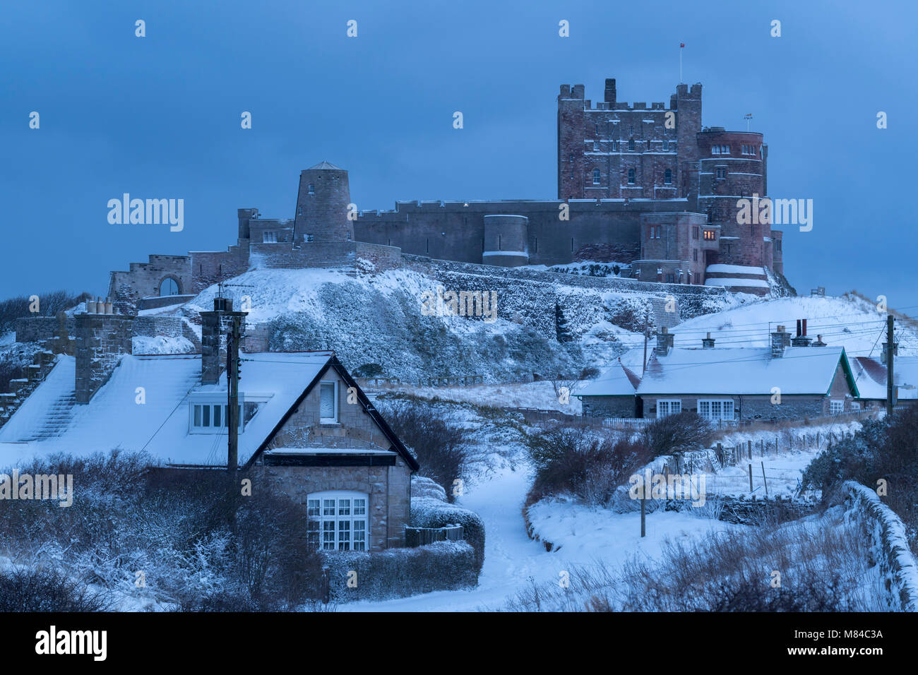 Village et Château de Bamburgh en hiver neige profonde, Northumberland, Angleterre. L'hiver (février) 2018. Banque D'Images