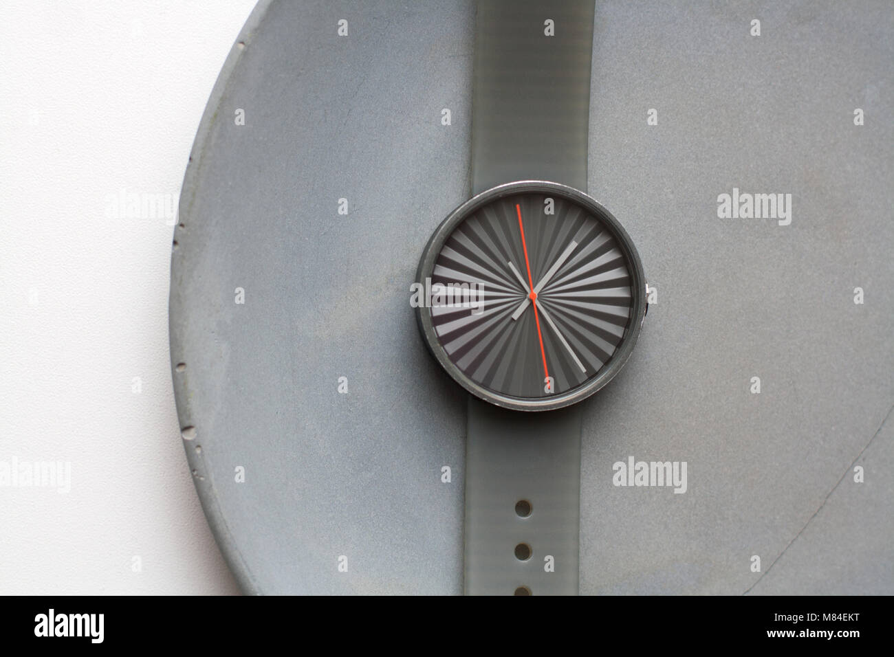 La relativité temps gris : montre-bracelet mécanique sans chiffres isolé sur une plaque de béton gris high angle view Banque D'Images