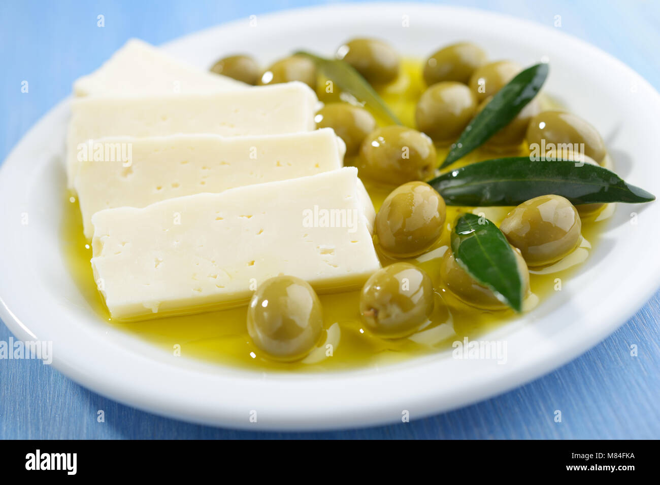Tranches de fromage Feta et olives vertes sur une plaque Banque D'Images