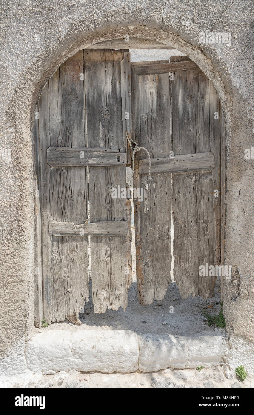 Emborio 607. Une vieille porte poussiéreuse je les rues d'Emborio sur Santorin, avec une brise légère et moderne bloc bouteille en plastique laissés sur le plancher Banque D'Images