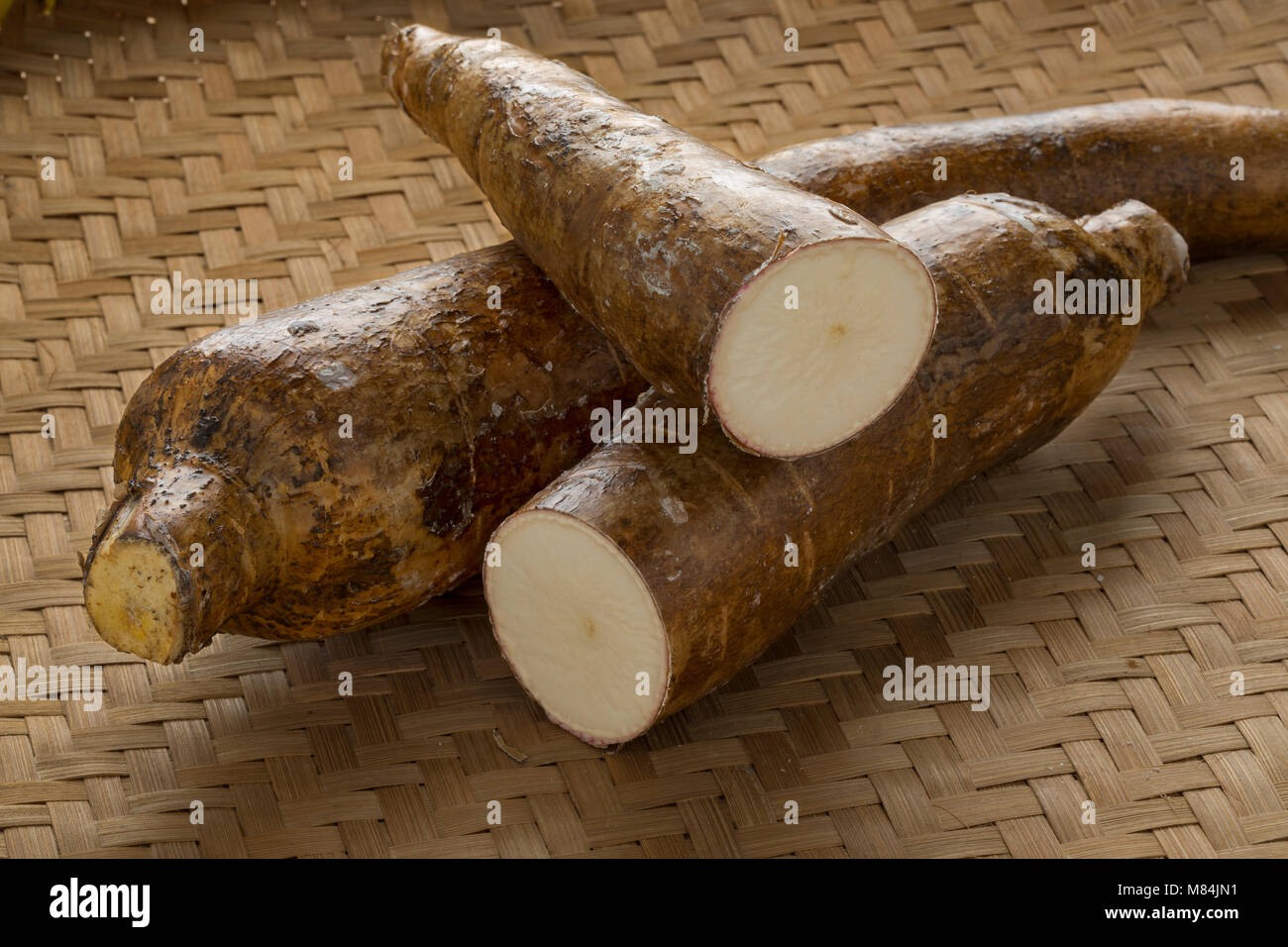Ensemble et la moitié les racines de manioc sur un arrière-plan en osier Banque D'Images