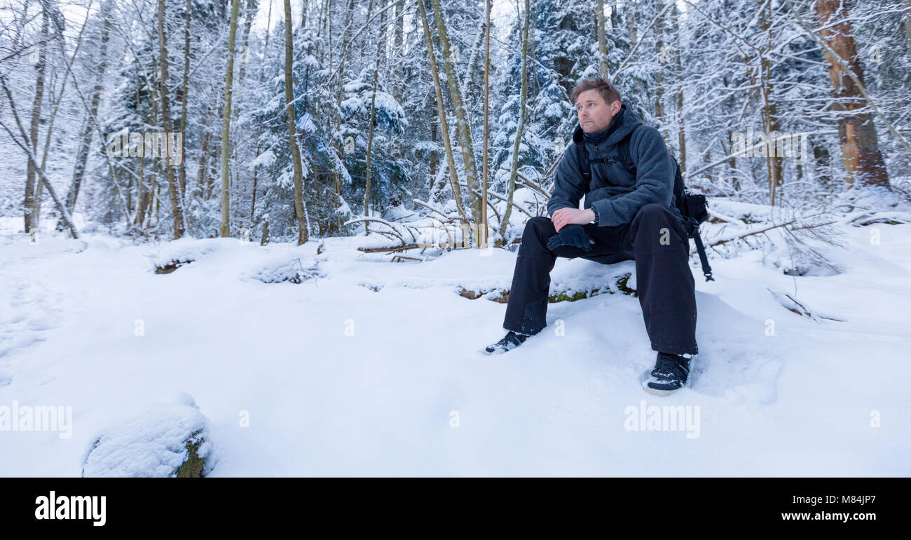 Homme adulte homme assis dans la forêt à l'écart en distance pensée dans un paysage d'hiver modèle libération : Oui. Biens : Non. Banque D'Images