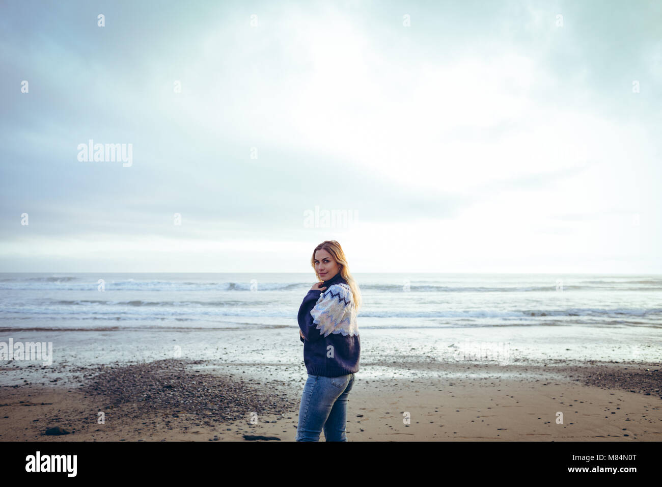 Femme debout sur une plage au crépuscule Banque D'Images