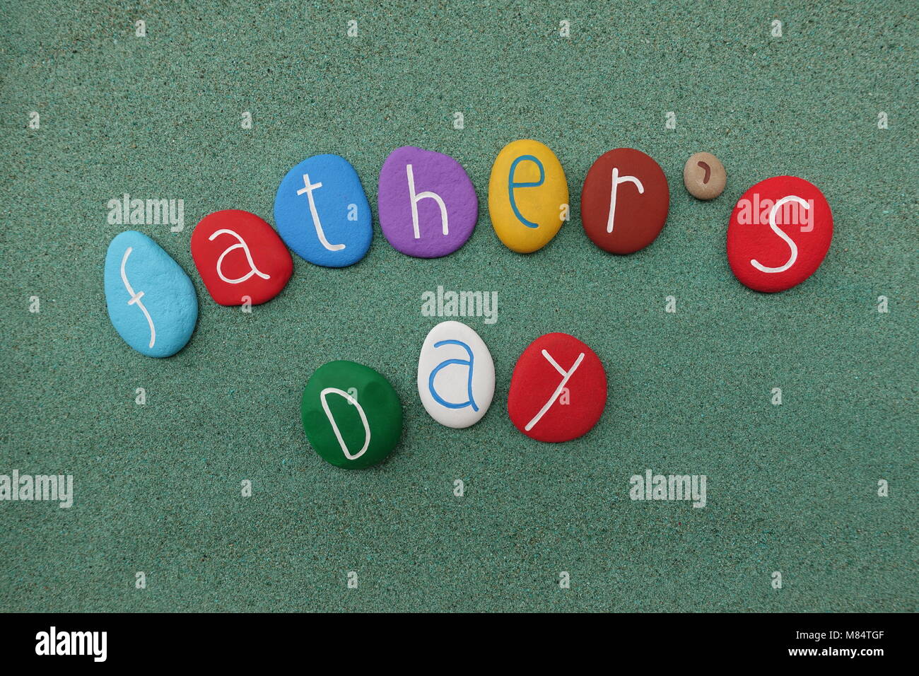 Le jour de père avec pierres multicolores sur sable vert Banque D'Images