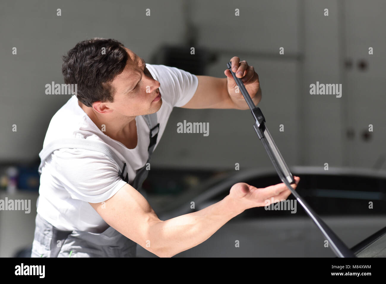 Mécanicien dans un atelier de réparation de voiture a inspecté l'état de l'essuie-pour l'usure afin d'assurer la sécurité Banque D'Images Mécanicien dans un atelier de réparation de voiture a inspecté l'état de l'essuie-pour l'usure afin d'assurer la sécurité Banque D'Images