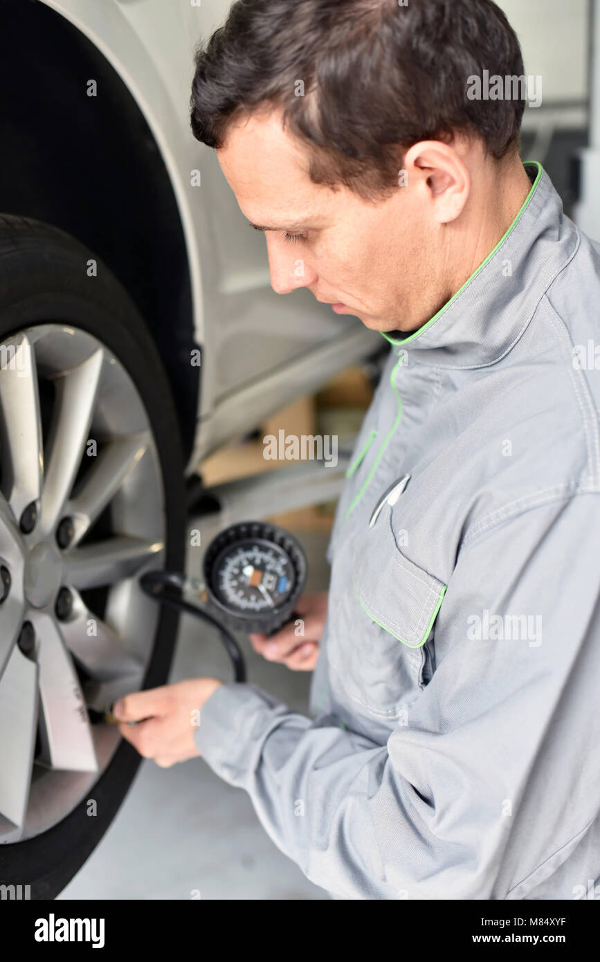 Mécanicien auto vérifie la pression d'air d'un pneu dans le garage Banque D'Images