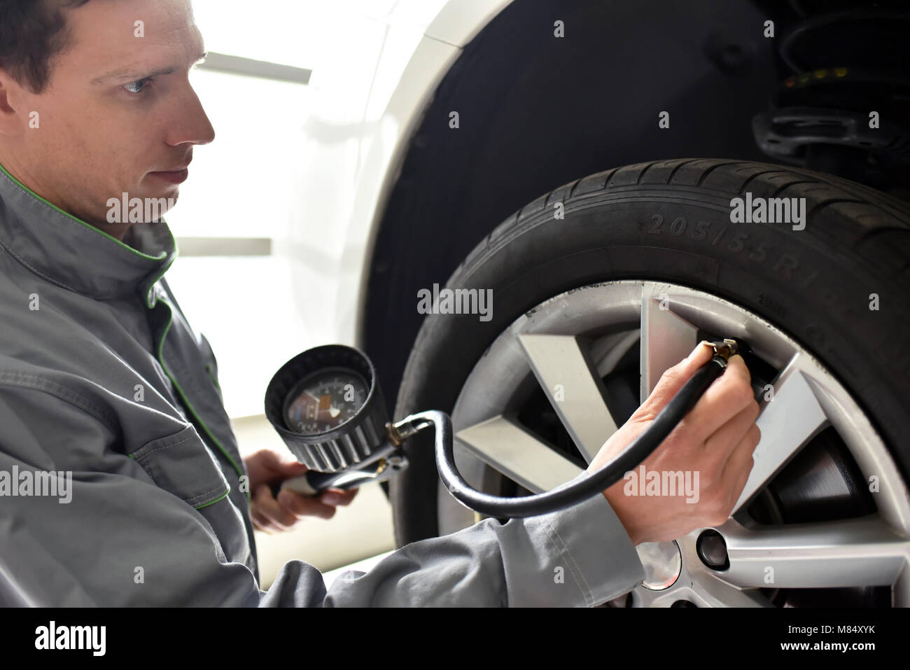 Mécanicien auto vérifie la pression d'air d'un pneu dans le garage Banque D'Images