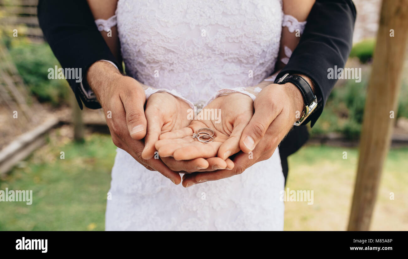 Close up of Bride and Groom mettant leurs mains et en tenue de mariage sur leurs paumes. Close up de deux anneaux de mariage sur coup nouvellement mariés Banque D'Images Close up of Bride and Groom mettant leurs mains et en tenue de mariage sur leurs paumes. Close up de deux anneaux de mariage sur coup nouvellement mariés Banque D'Images