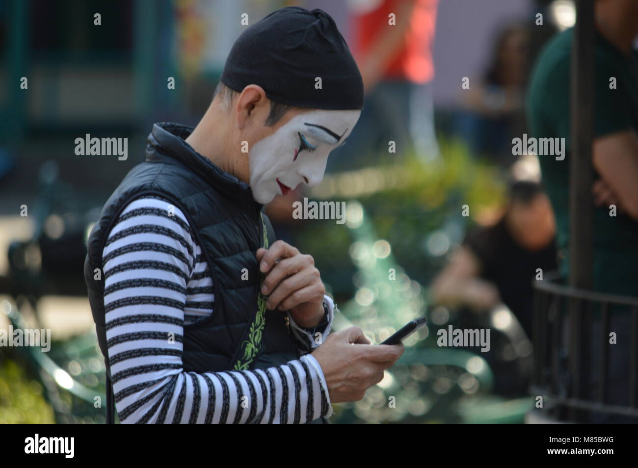 Un artiste mime regardant son téléphone Banque D'Images