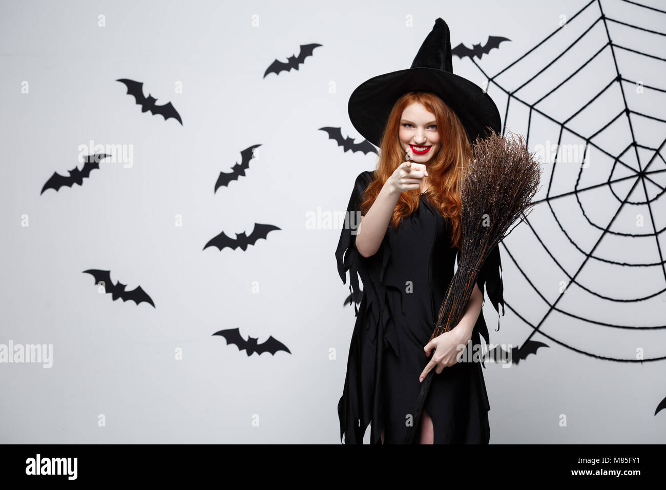 Concept - Happy Halloween sorcière élégante avec balai halloween faisant  montre de l'index sur le côté Photo Stock - Alamy