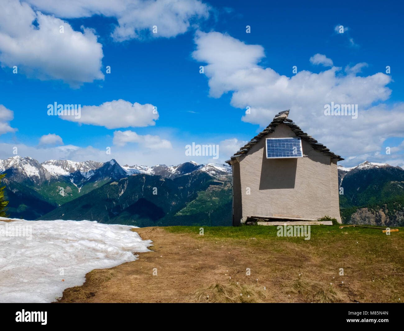 Petite maison sur une crête de montagne avec panneau solaire Ciel bleu avec quelques nuages blancs Banque D'Images