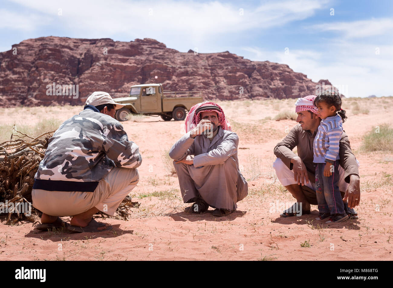 Un groupe de Bédouins accroupie avec petite fille dans le désert de Wadi Rum en Jordanie. Banque D'Images