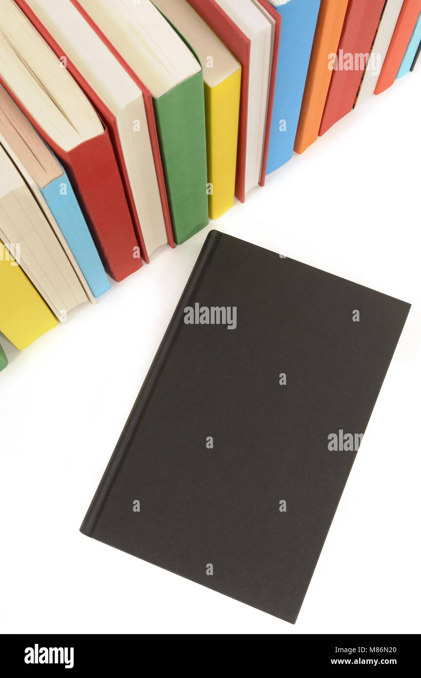 Un livre noir avec rangée de livres colorés isolé sur un fond blanc. Banque D'Images