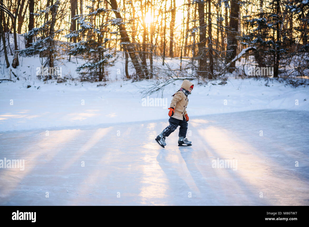 Boy le patin à glace sur un lac gelé Banque D'Images