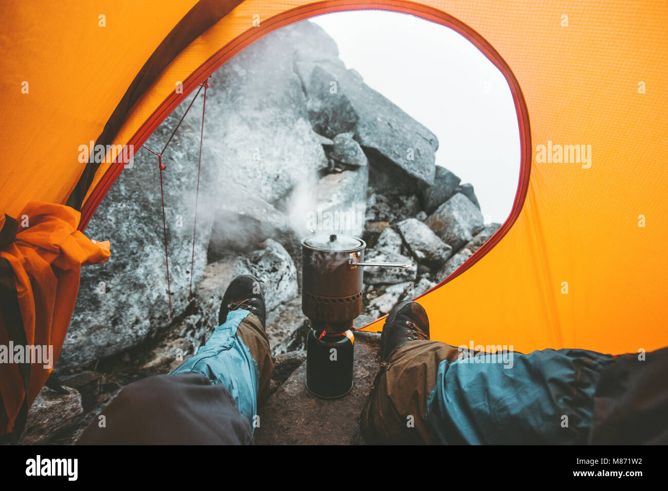 L'homme cuisine voyageur dans le pot brûleur cuisinière vous relaxant dans tente de camping de vie voyage vacances vacances montagne plein air concept Banque D'Images