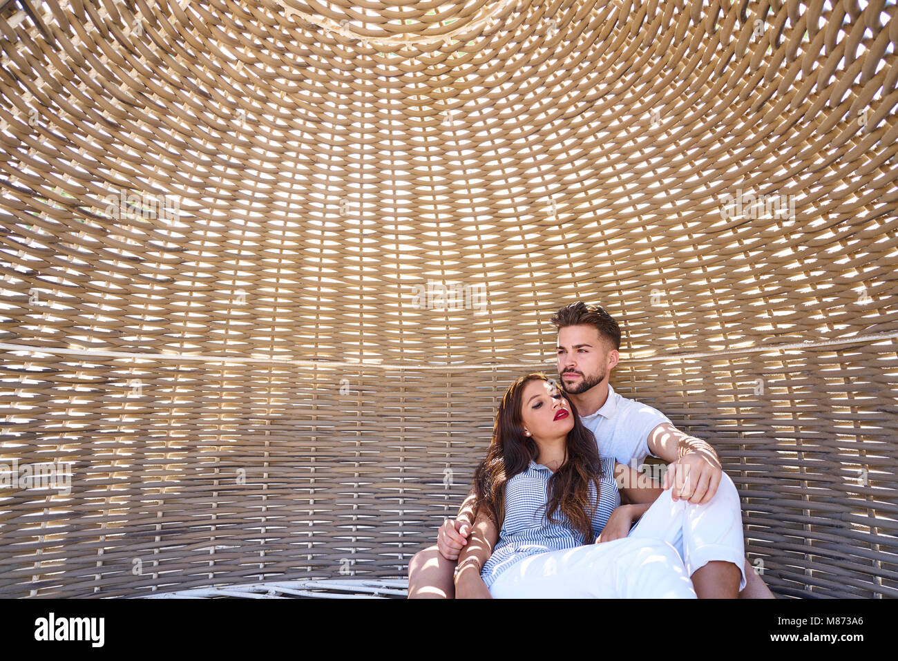 Couple de touristes à l'intérieur d'un parasol de plage détendue en été locations Banque D'Images