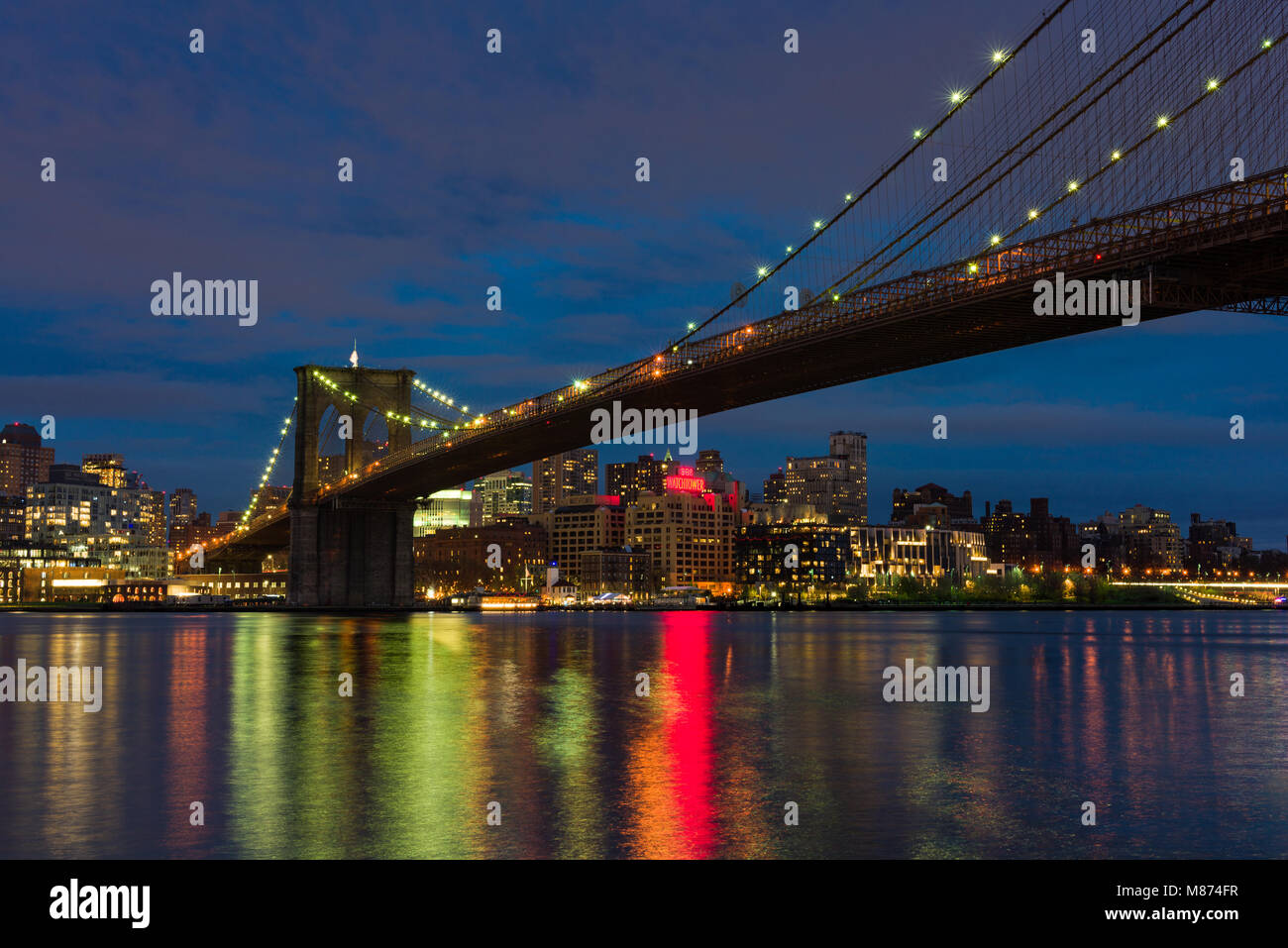 Le Pont de Brooklyn Brooklyn et illuminé à la tombée de la nuit avec les reflets dans l'East River, New York, USA Banque D'Images