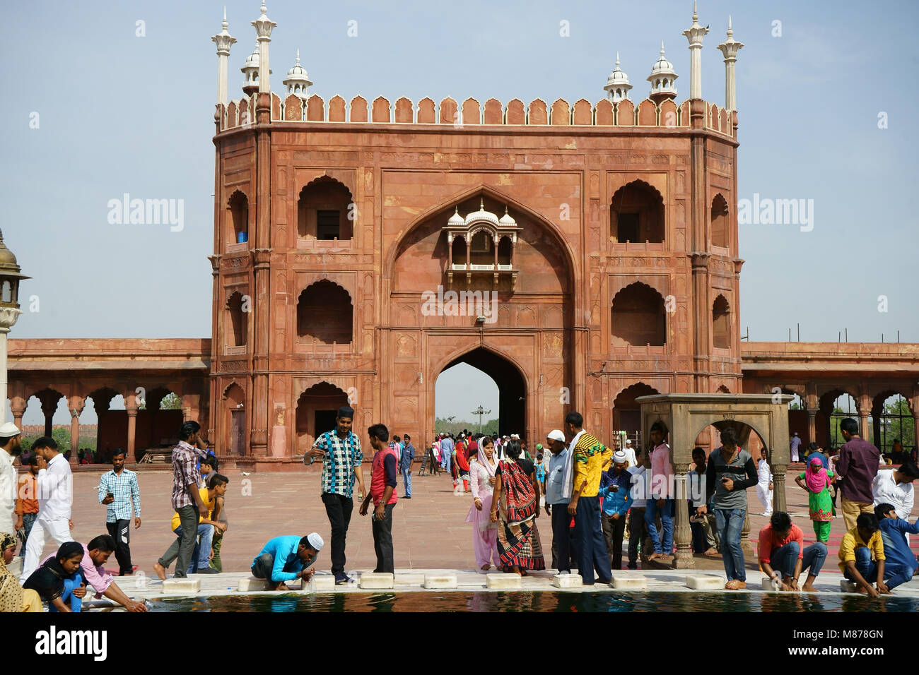 Les femmes et les hommes musulmans se laver à l'intérieur du bassin de la cour intérieure de la mosquée Jama Masjid avec la porte de l'Est, après la prière du vendredi, Old Delhi, Inde Banque D'Images