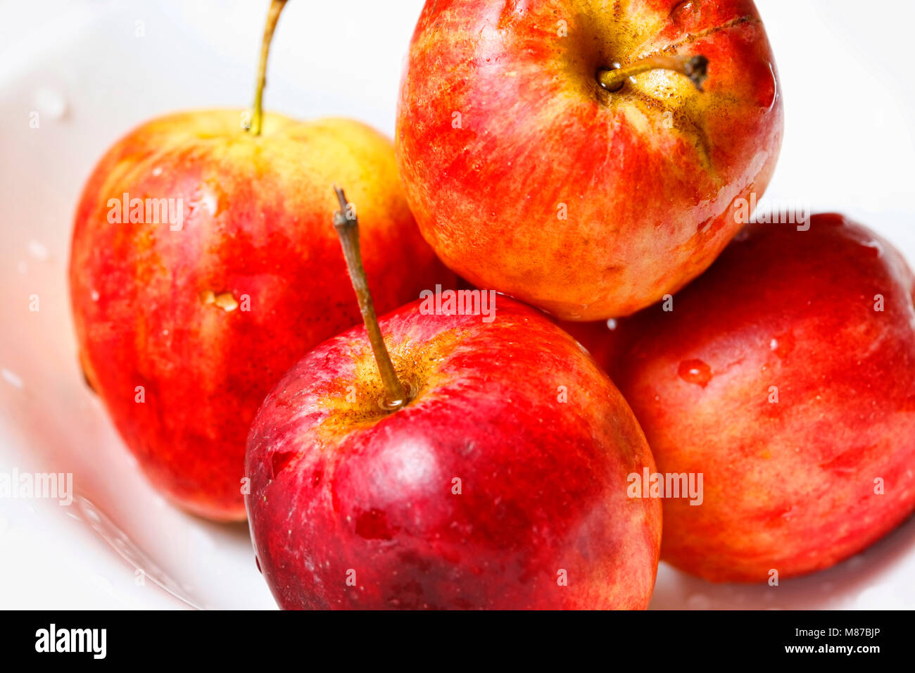 Pommes rouges en gouttes close-up sur fond blanc Banque D'Images