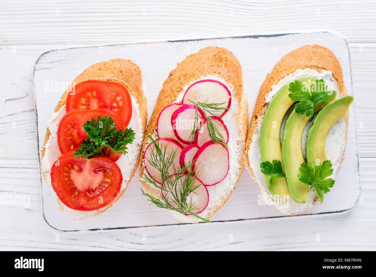 Mini-sandwiches au fromage à la crème, légumes et de l'avocat. Choix de sandwichs sur fond blanc, vue du dessus. Mise à plat Banque D'Images