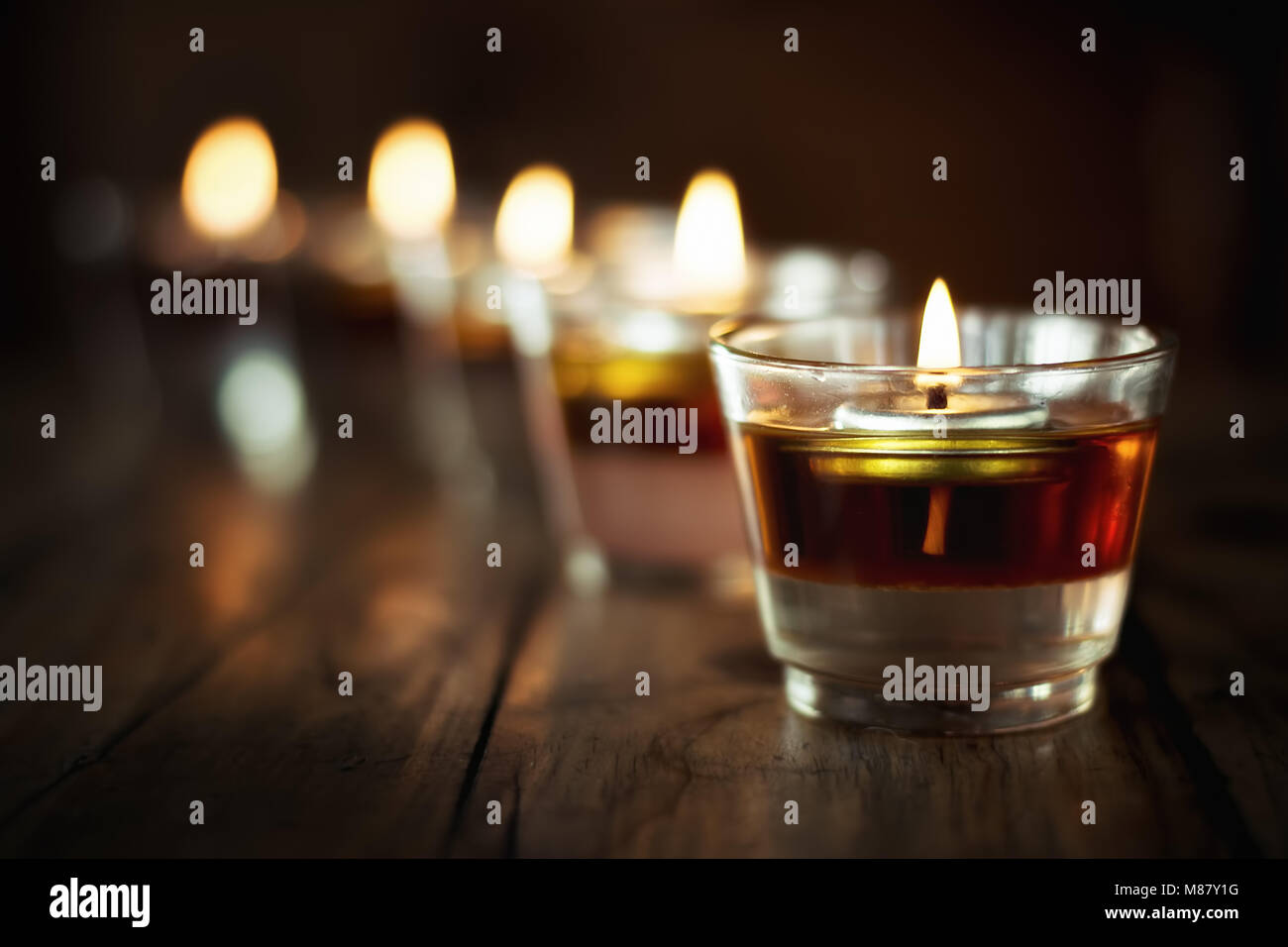 Bougie votive en verre. Bougie dans pot on wooden table Banque D'Images