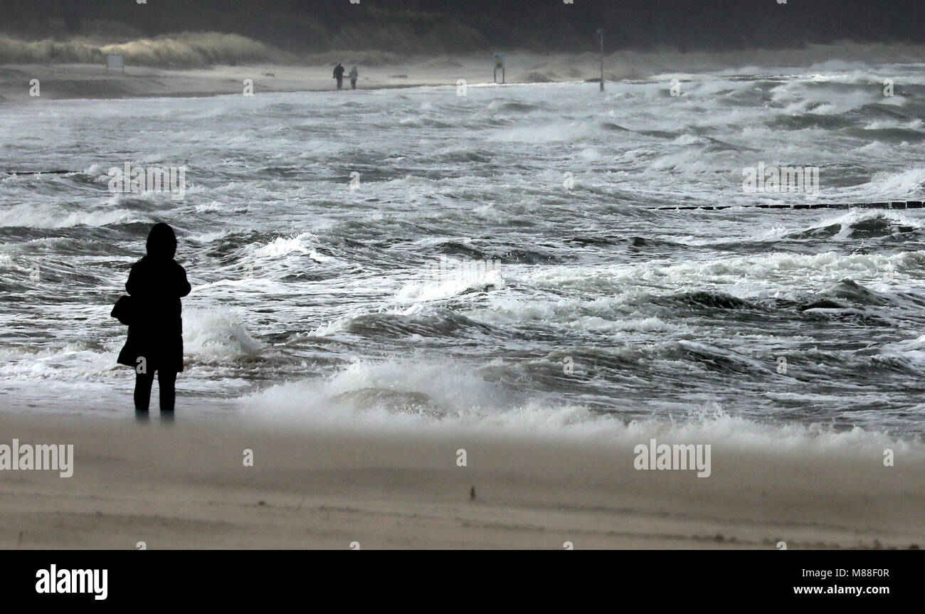 16 mars 2018, l'Allemagne, Warnemuende : Malgré les vents forts, les gens d'aller marcher le long de la mer Baltique. Les températures glaciales et les vents orageux repoussent l'Eveil du printemps pour encore une couple de jours. Photo : Bernd Wüstneck/dpa-Zentralbild/dpa Banque D'Images