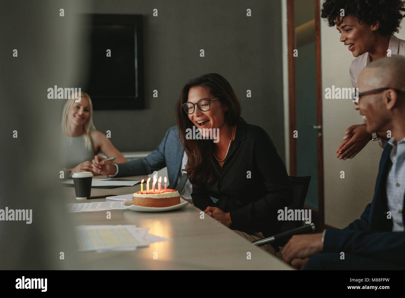 Célébration d'anniversaire surprise d'une avocate salariée lors d'une réunion du personnel. Les employés de bureau surprenant collègue avec un gâteau pour son anniversaire durin Banque D'Images