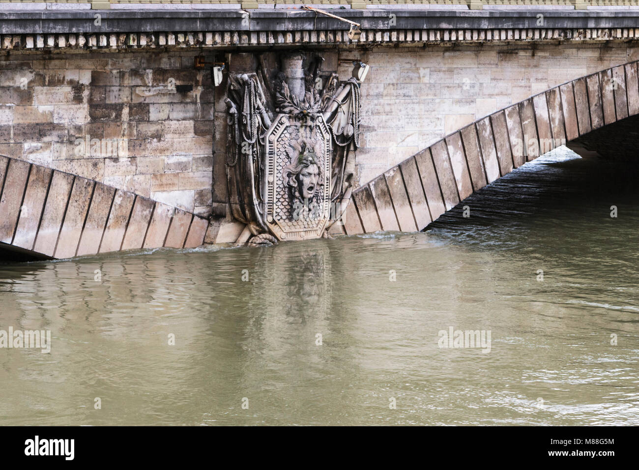 Pierre partiellement submergé de secours en tête de Méduse militariste armoiries sur le pont des Invalides à Paris en janvier 2018 inondation. Banque D'Images