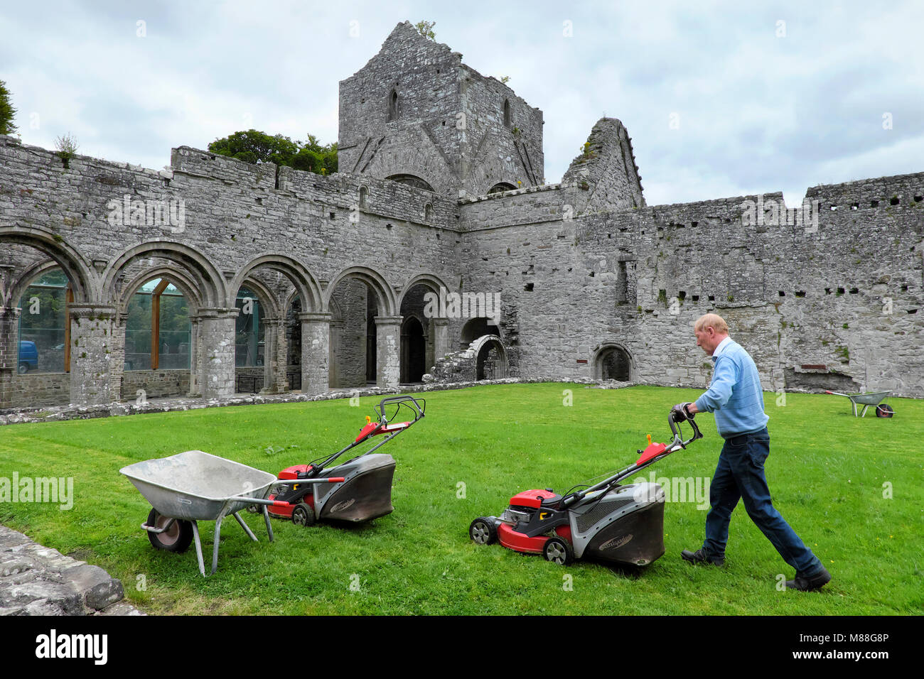 Un vieil homme / concierge / gardien tond la pelouse, l'abbaye de Boyle, Sycamore Crescent, Boyle, comté de Roscommon, Irlande Banque D'Images